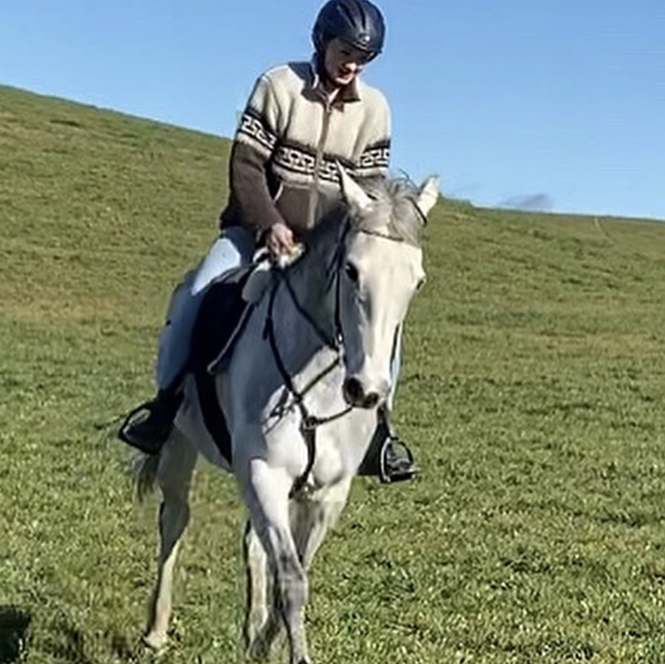 Nia riding in a wide green field under a big sky